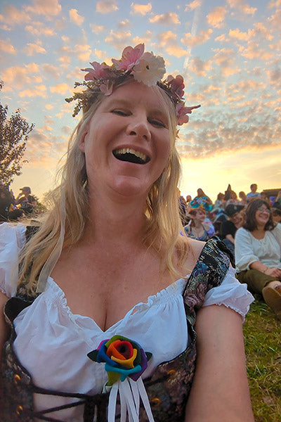 Photo of Summer Heidt at the Pennsylvania Renaissance Faire with a white blouse, corset, and flowers in her hair, at sunset